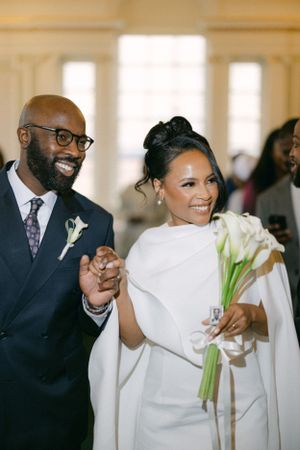 Newlywed couple walking down aisle with white calla lily bouquet.