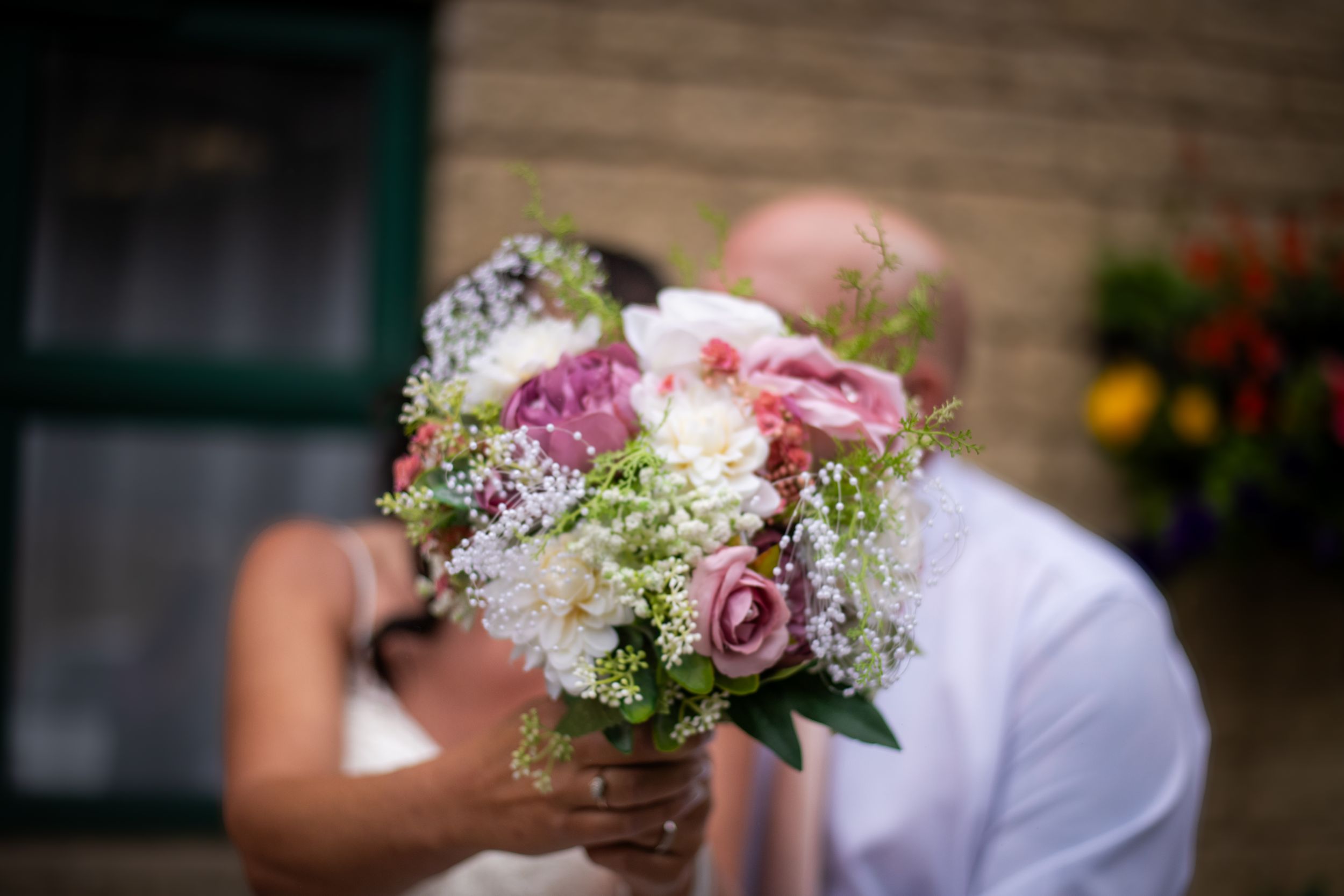 Romantic bridal bouquet with pink roses and baby's breath against blurred background.