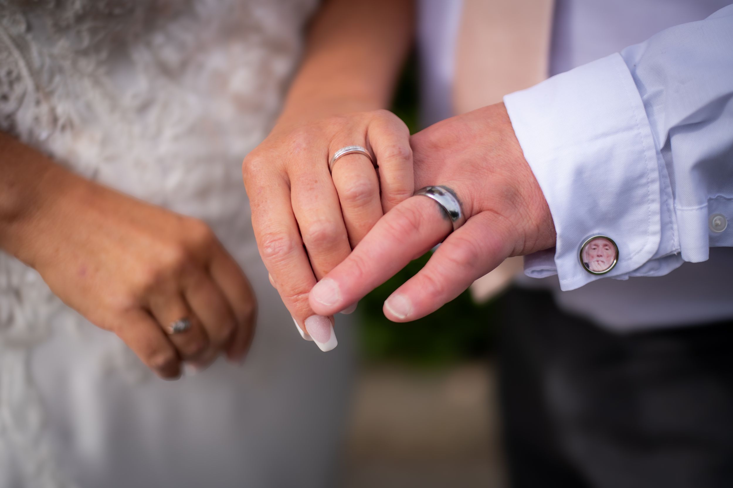 Detail shot of wedding bands on hands during ceremony exchange.