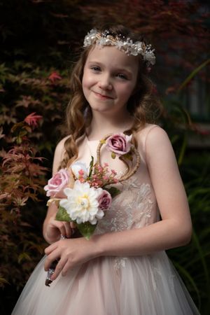 Enchanting portrait with floral crown and pink roses against Japanese maple backdrop.
