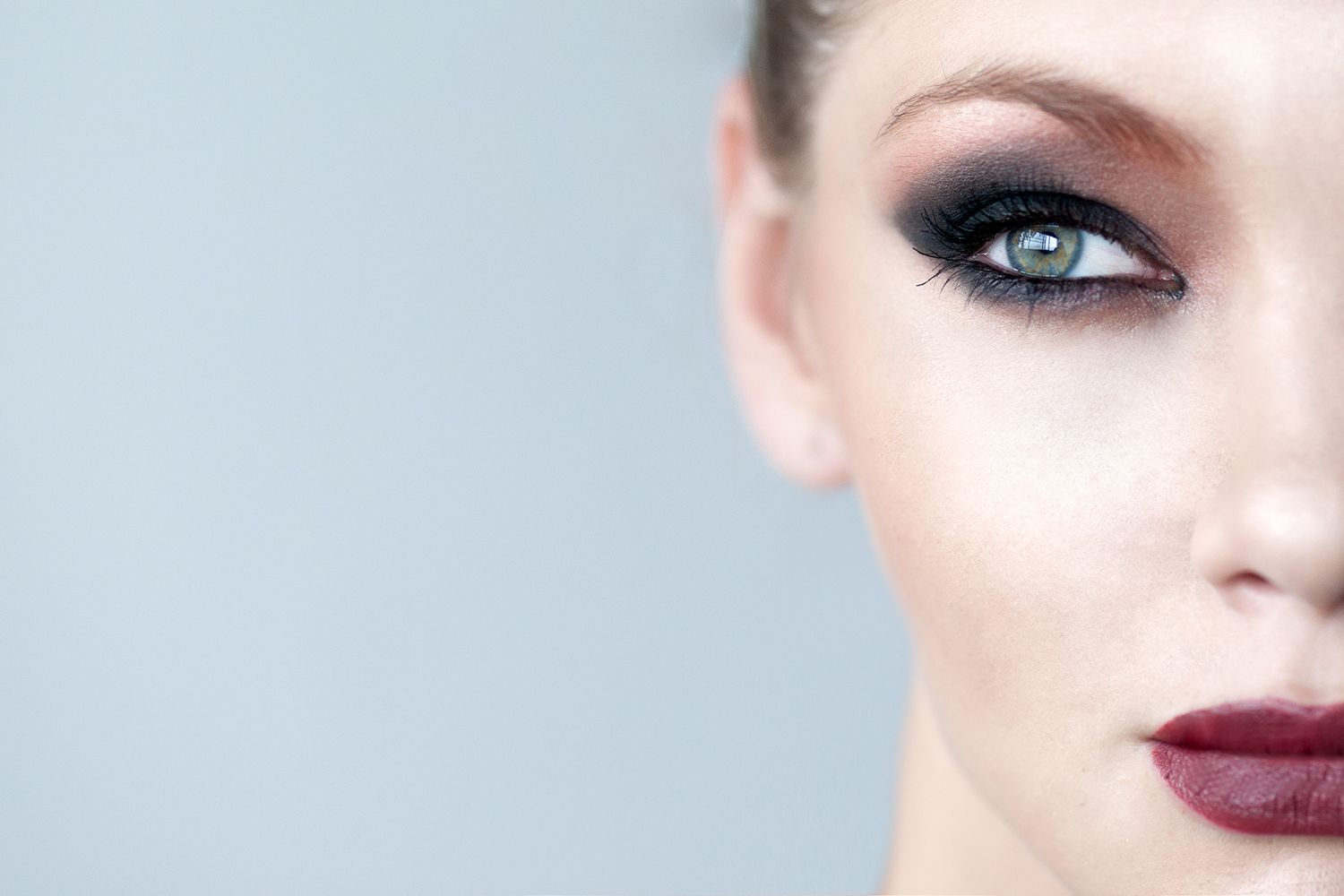 Close-up beauty portrait featuring dramatic eye makeup and deep red lipstick.