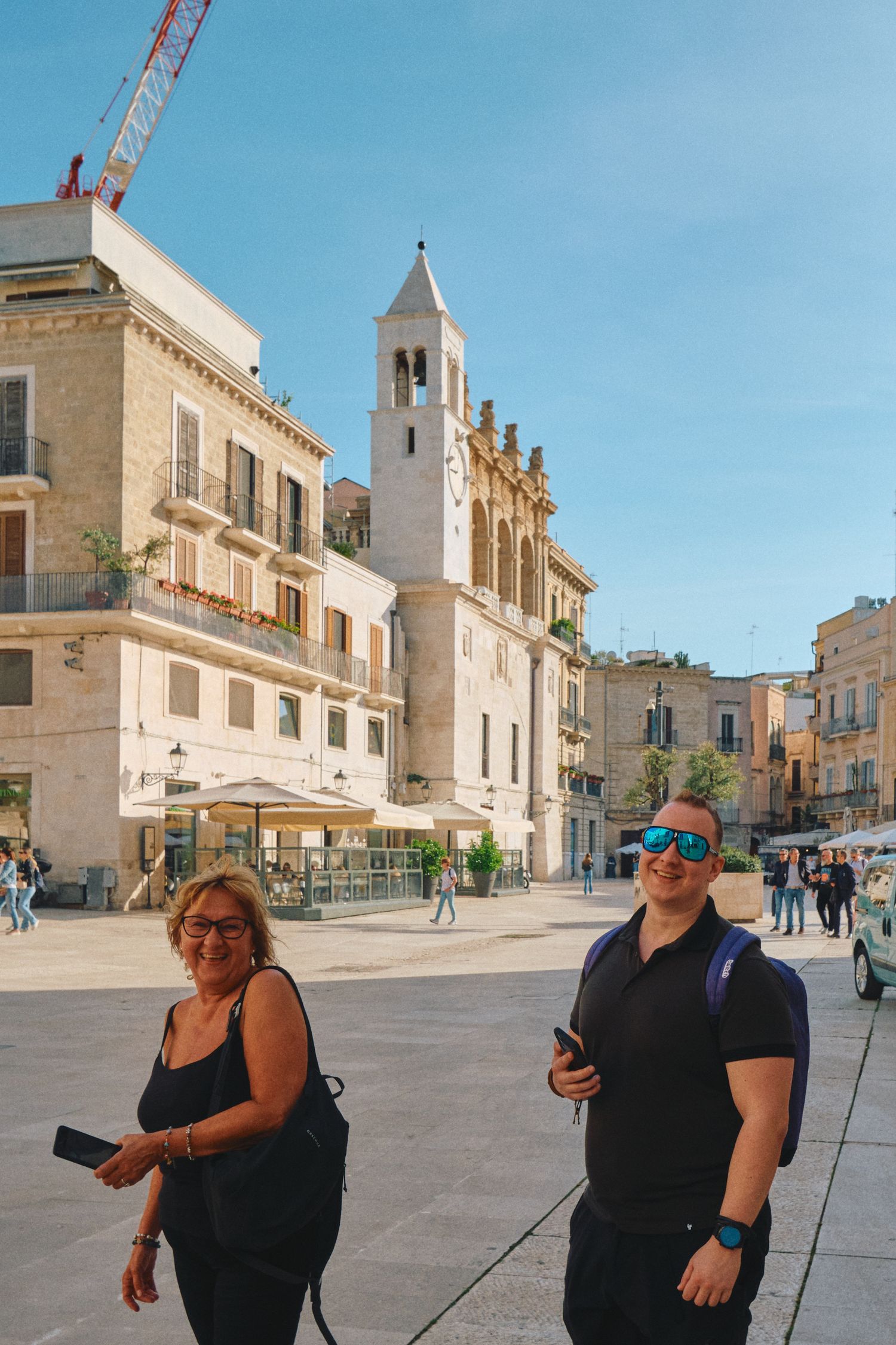 Historic white church and buildings in an Italian town square on a sunny day.