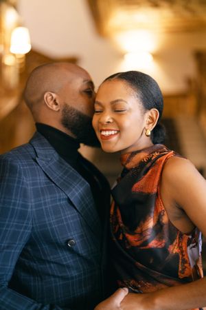 An intimate moment captured between a couple sharing laughter in warm indoor lighting.