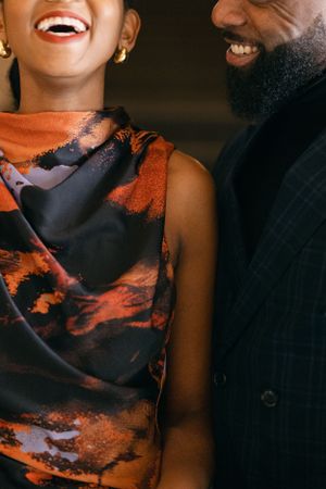 A candid moment of shared laughter showing details of formal attire in orange and navy.