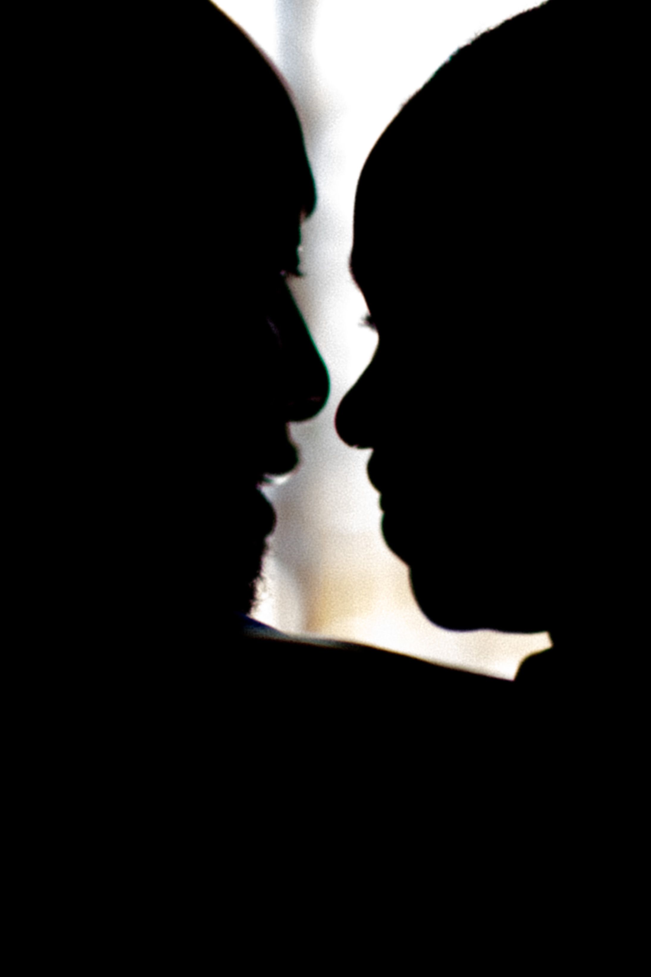Two silhouettes face each other in dramatic black and white contrast against a white background.