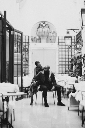 A romantic black and white photo of a couple sharing an intimate moment in an elegant hallway setting.