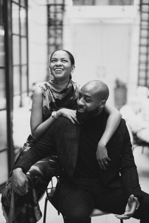A joyful couple shares a candid moment while sitting together in a bright interior space.