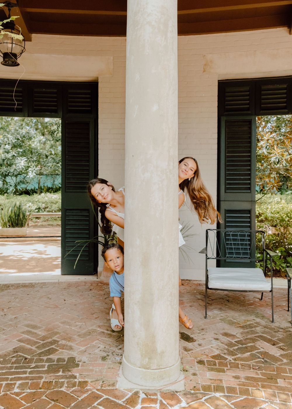 Sequence of playful poses between white columns on a brick patio.