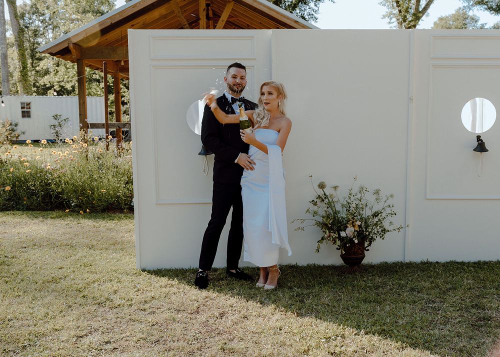 Wedding couple sharing intimate moment against white wall outdoors.