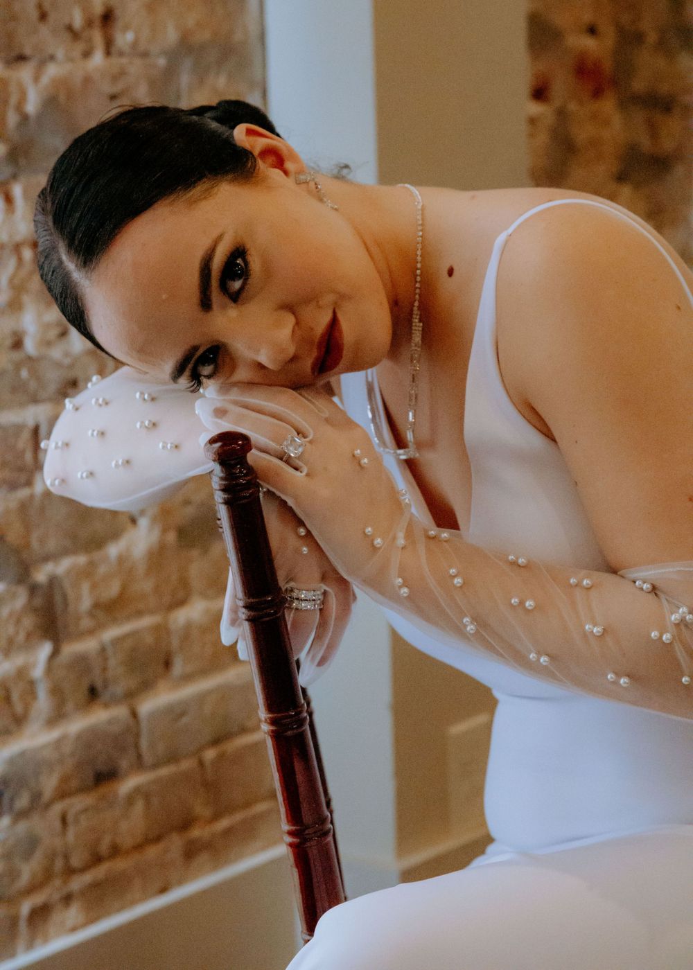Elegant bridal portrait series against exposed brick wall with delicate details.