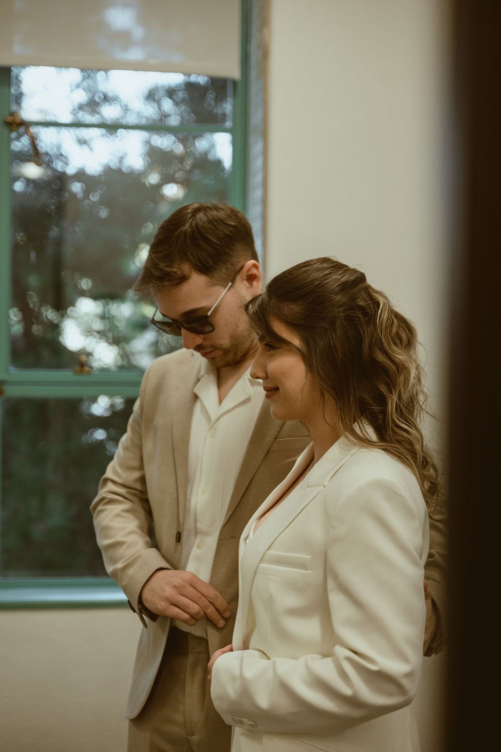 Intimate indoor portrait of couple in coordinating light colored formal wear.