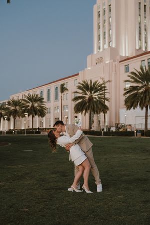 Romantic moment captured outside a grand pink Art Deco building.
