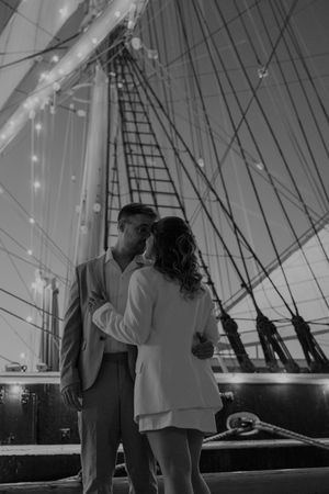 Romantic silhouette moment aboard a ship with string lights overhead.