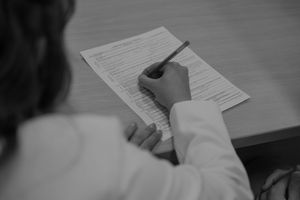 Couple signing paperwork on a desk together in black and white.