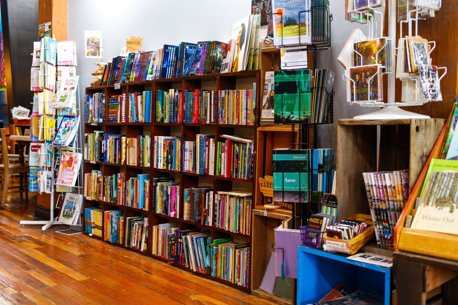 Long wall of wooden bookshelves filled with colorful books in a bookstore.