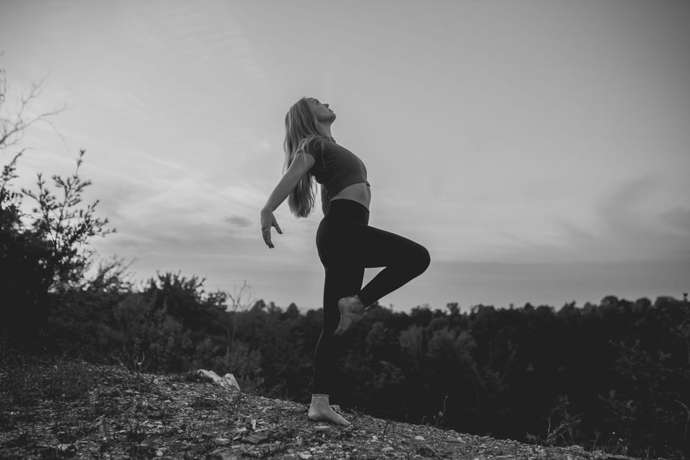 Silhouette of someone jumping on a hill at sunset creating a dramatic outdoor scene.