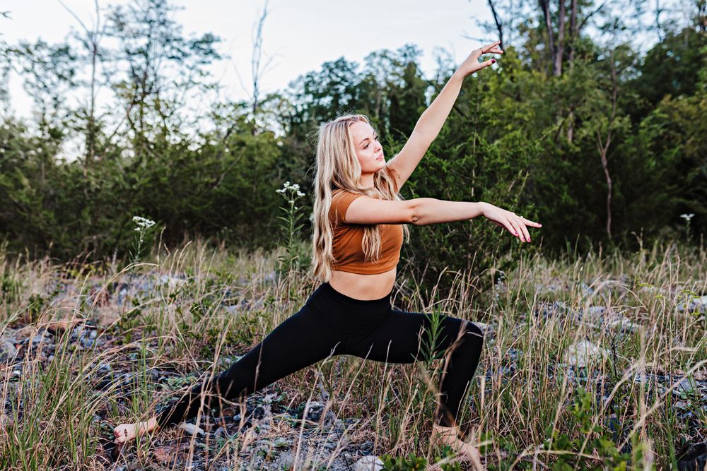 A dancer strikes a powerful pose in a field during golden hour lighting.