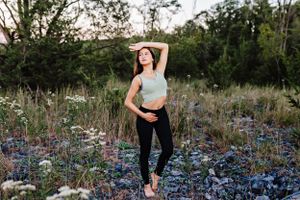 A dancer stretches in a field of bluebonnets during golden hour.