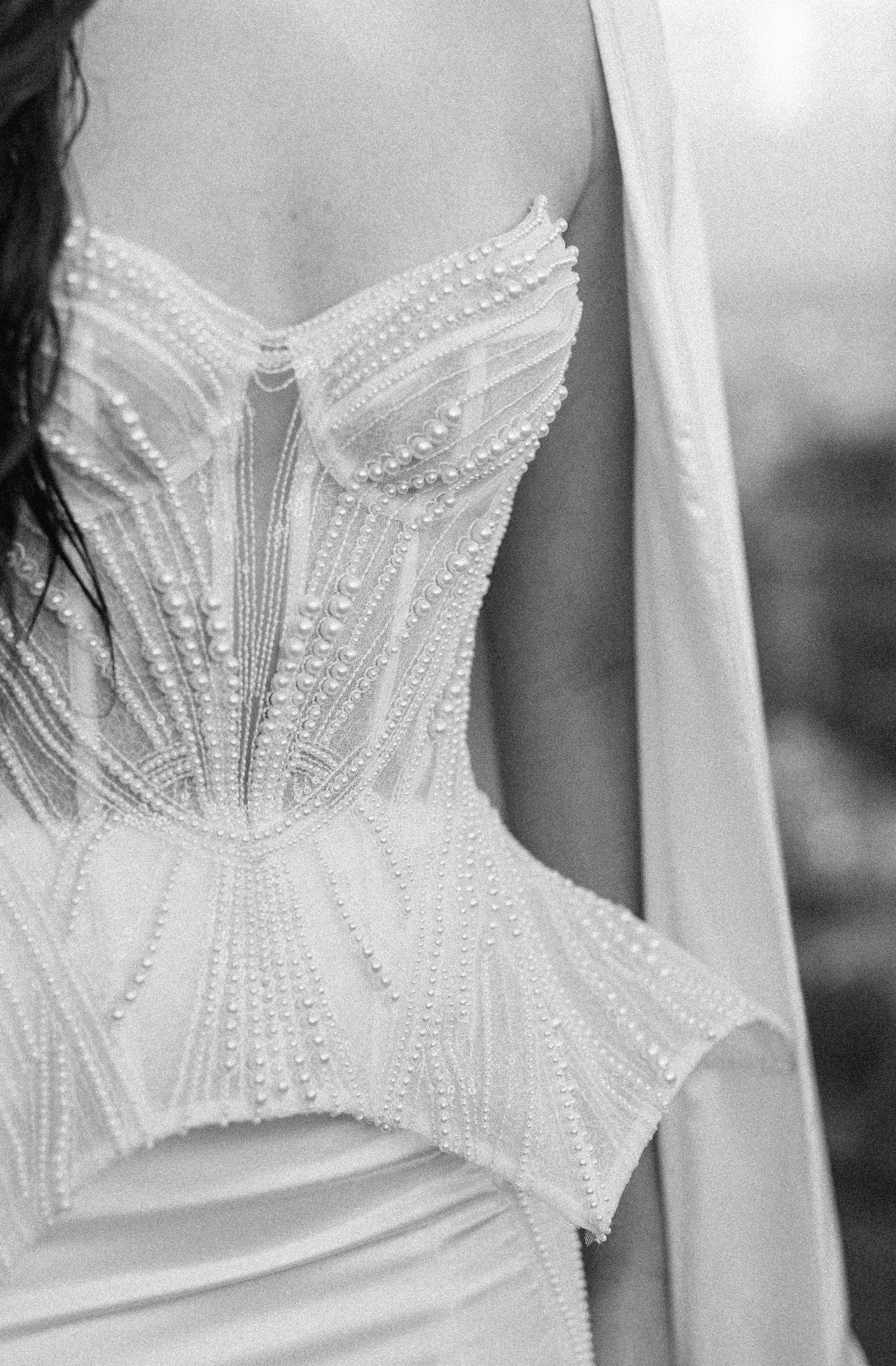 Close-up detail of intricate beaded white wedding dress bodice with geometric patterns.