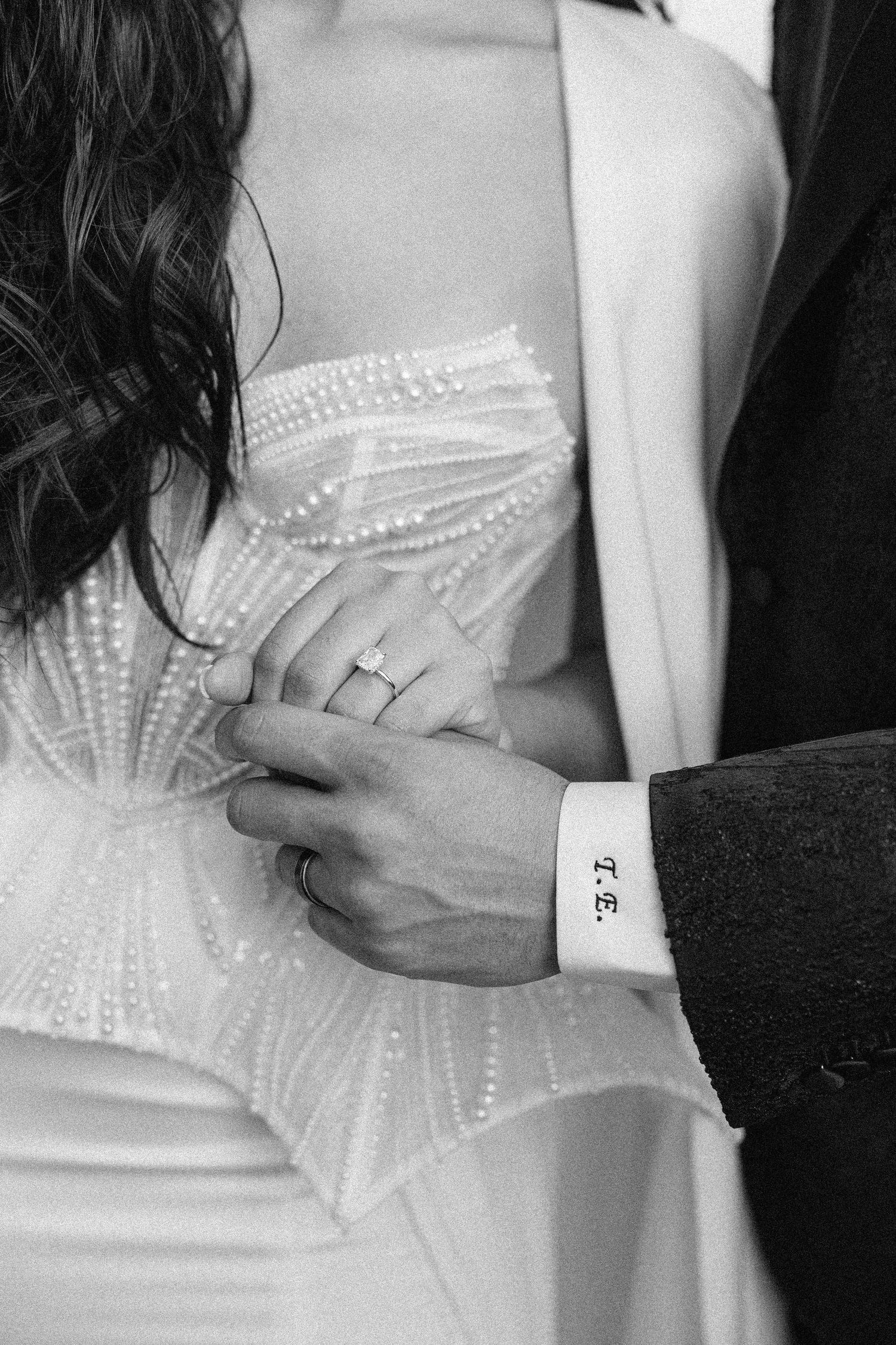 Black and white detail of engagement ring and formal dress beadwork.