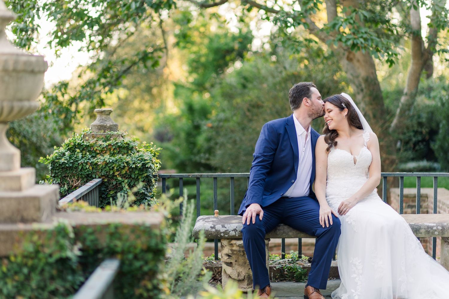 Bride and groom snuggle on a bench in the gardens at the Virginia House in Richmond, VA.