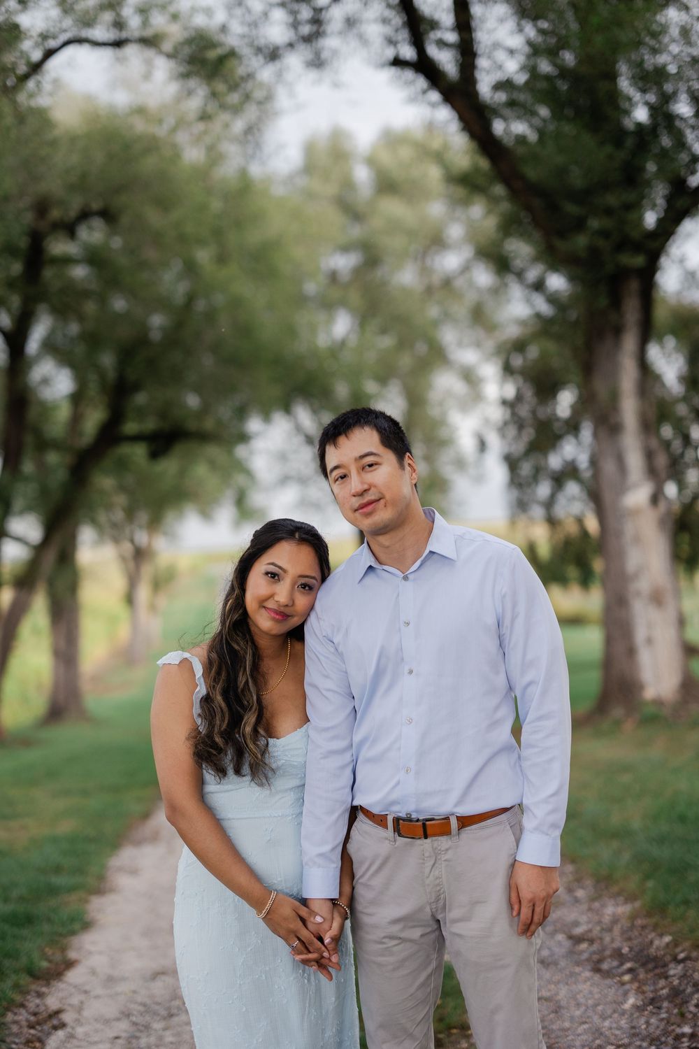 A couple poses together on a tree-lined path during a romantic outdoor photo session.