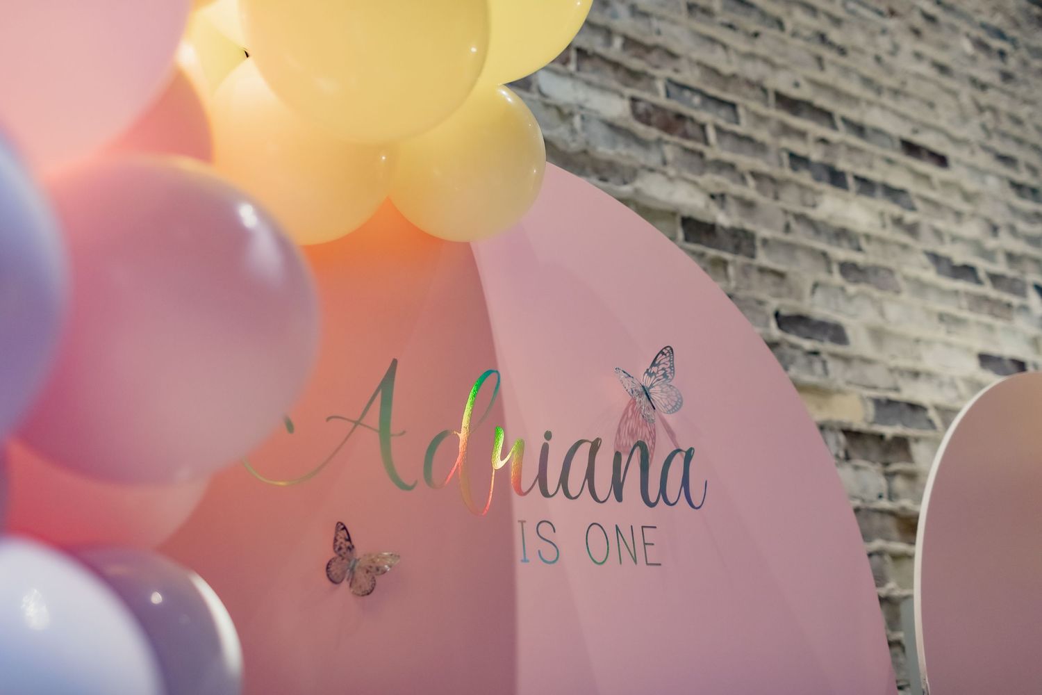 Pink birthday party backdrop with balloon decorations and butterfly accents.
