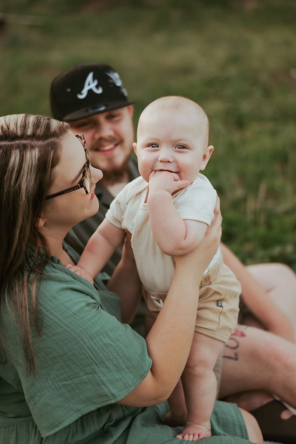 A family sharing joyful moments together while sitting on grass outdoors.