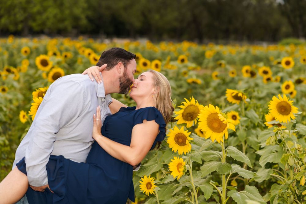 A romantic couple embraces in a vibrant field of blooming sunflowers on a sunny afternoon.