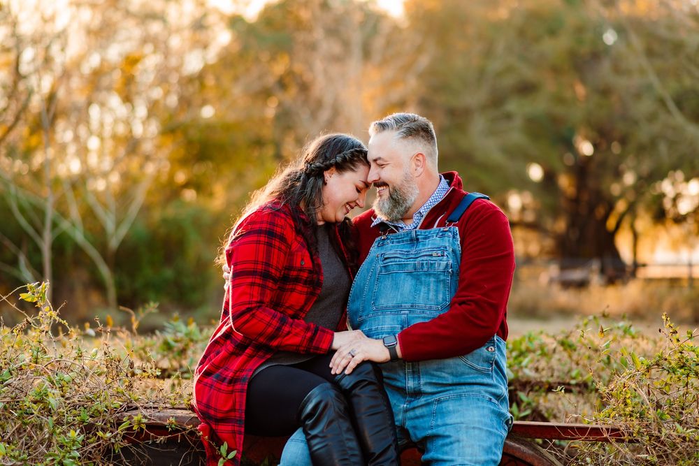 Couple sitting close together touching foreheads romantically outdoors in autumn park setting.