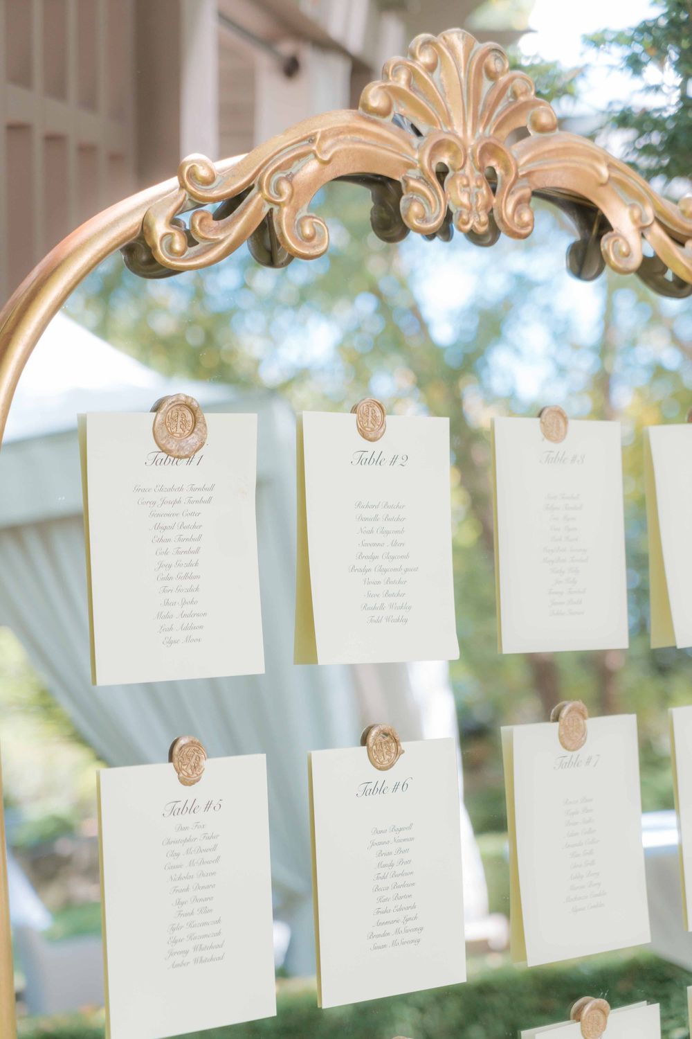 Elegant ornate gold frame displaying wedding seating chart cards.