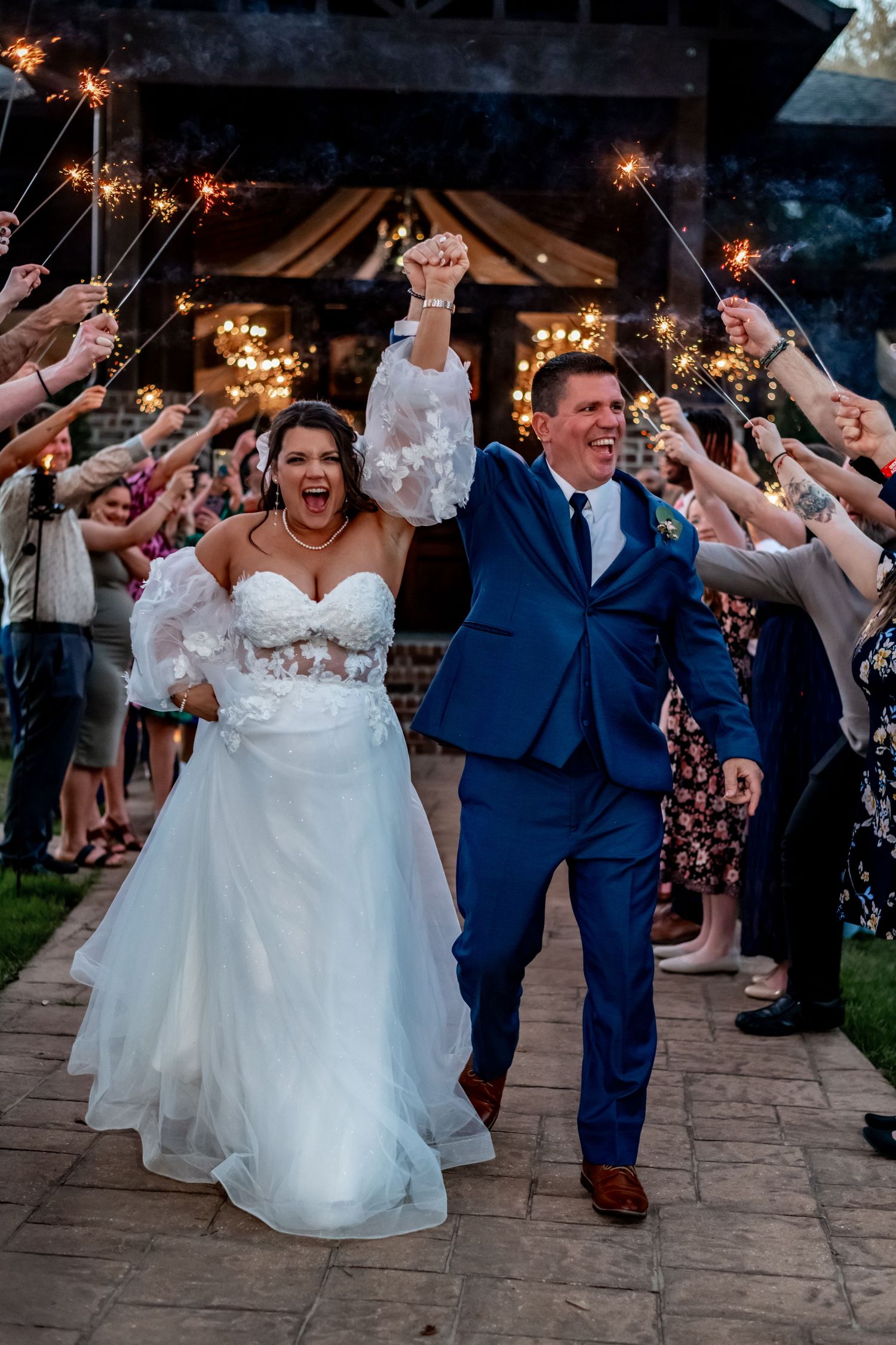 Wedding exit with sparklers as couple celebrates with guests outside venue.