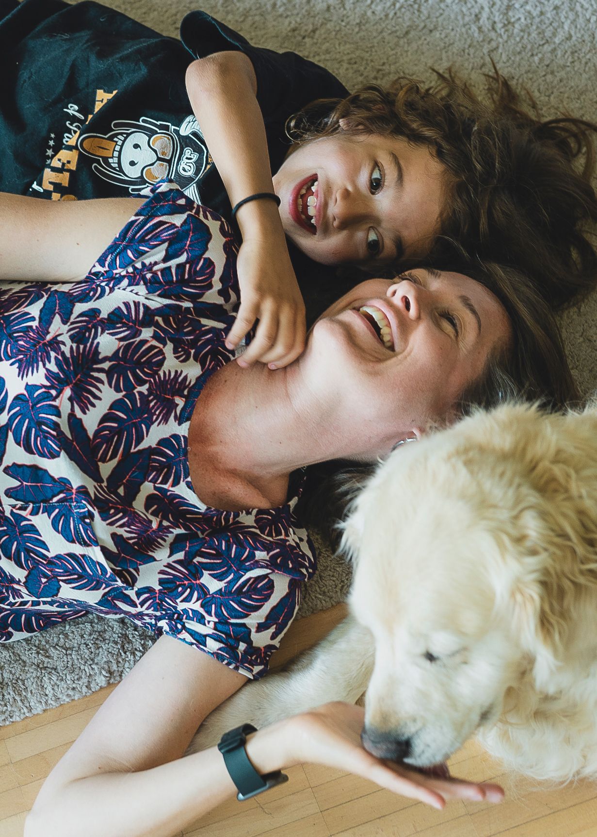 Mother and son are lying on the ground and laughing.