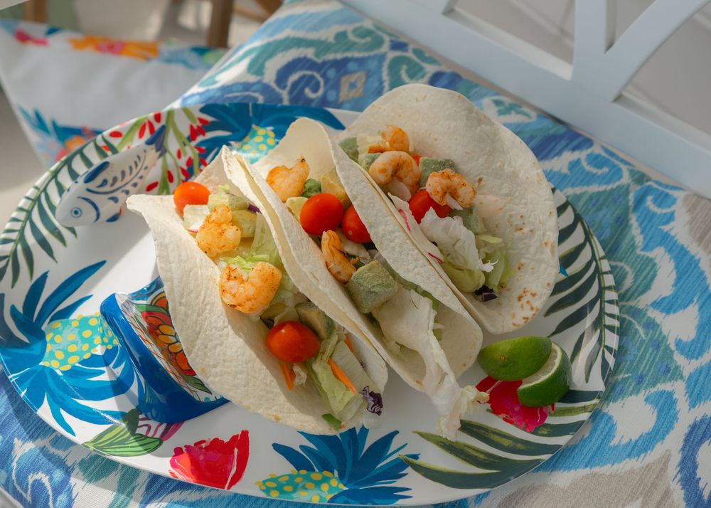 three fish and avocado tacos on a colorful blue and white platter