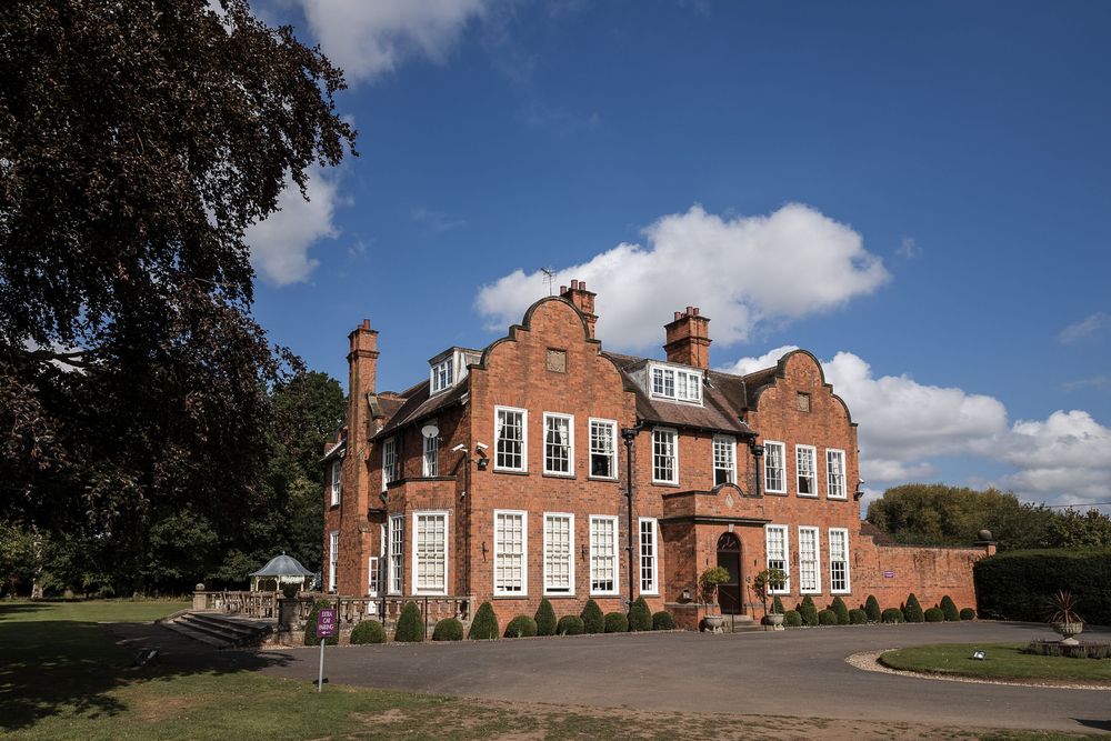 Kelham House wedding venue under a blue sky with fluffy clouds.