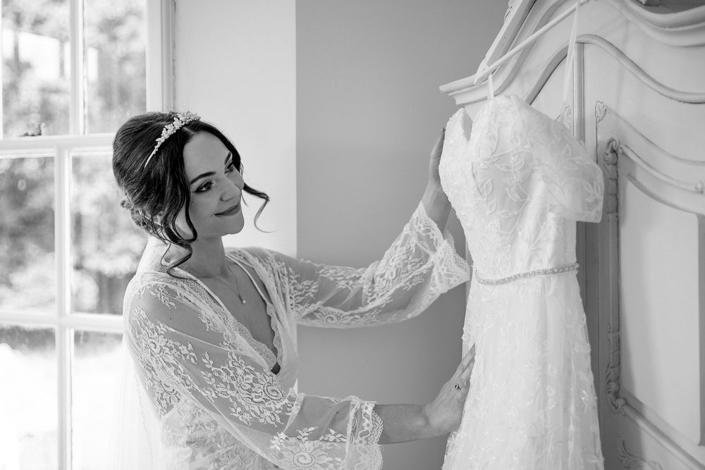 Black and white image of a bride getting ready in a lace wedding dress at Kelham House.