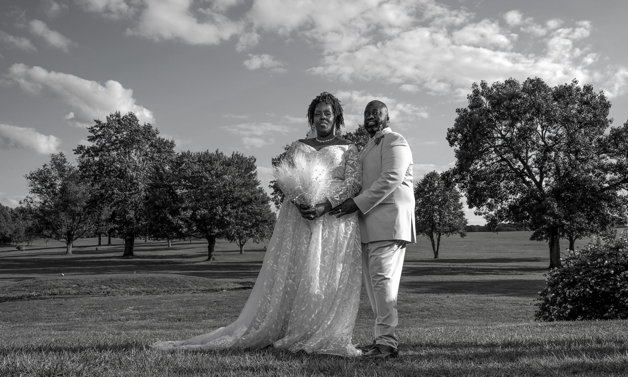 A black and white wedding photo collage showing outdoor scenes in an orchard with romantic poses and flowing dresses.