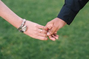 Two hands holding together with a backadrop of grass