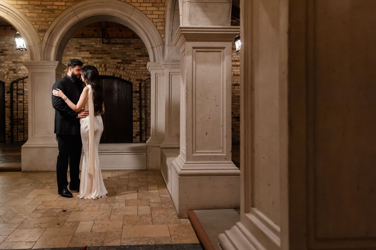 Romantic photo series under a pink floral arch with candles in an industrial-style venue.