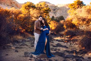Couple embraces on rocky terrain during golden sunset.