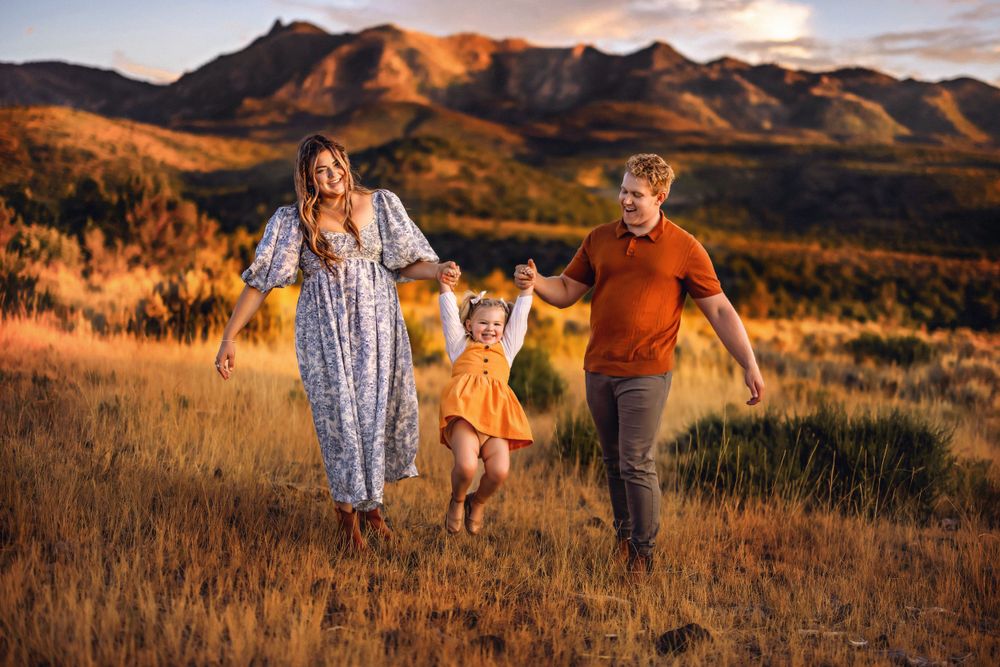 A family holds hands while running through a golden mountain meadow at sunset near Pine Valley Utah, Southern Utah
