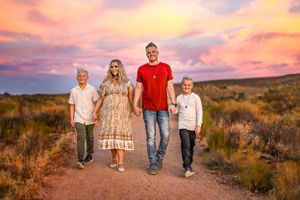 A family walks together on a desert trail during a colorful sunset in Southern Utah