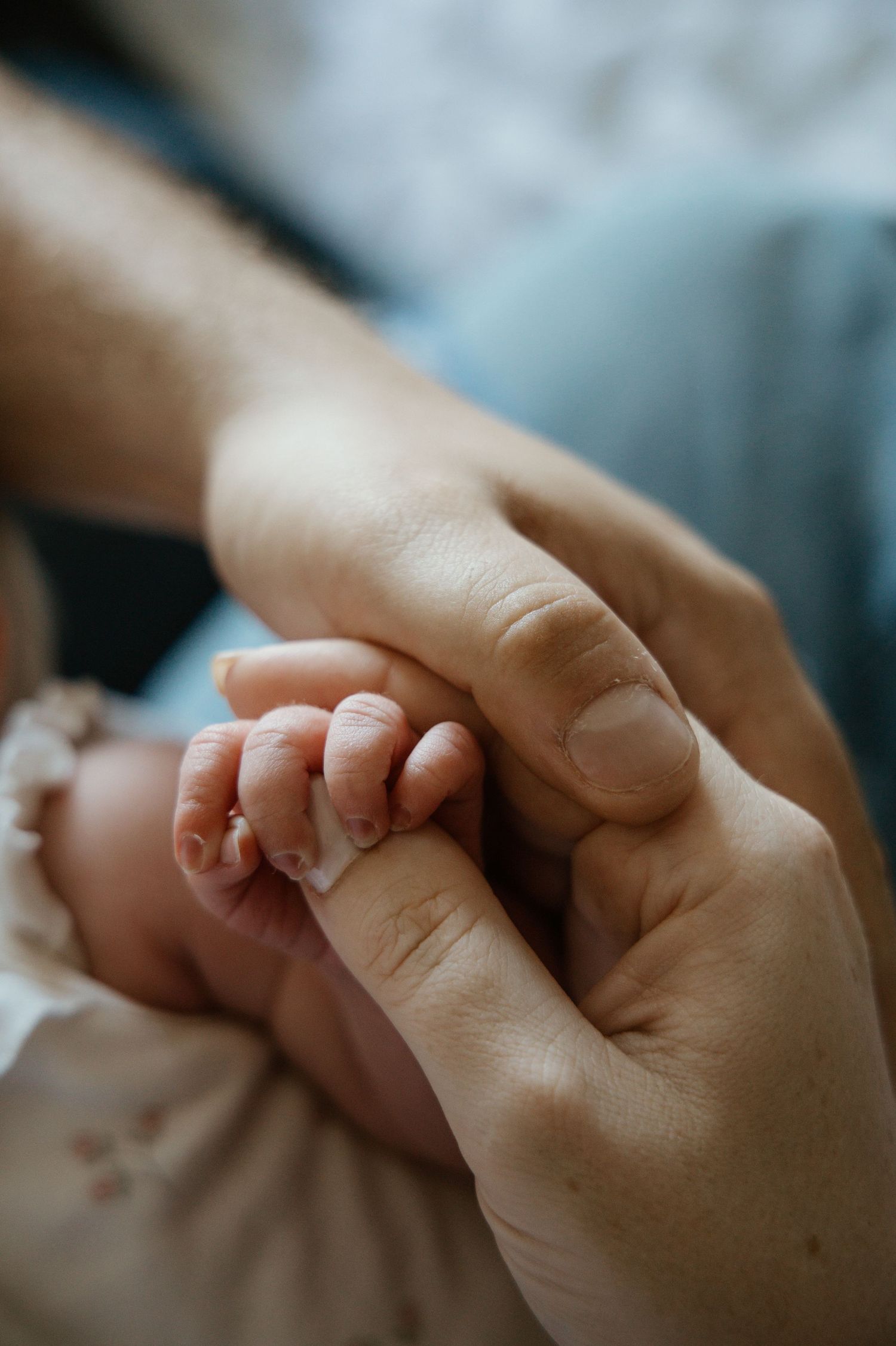 Close-up of tiny newborn baby feet resting on a tattooed fathers arm wearing a silver watch.