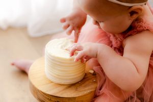 A baby in a diaper plays with wooden stacking toys on a light-colored surface.