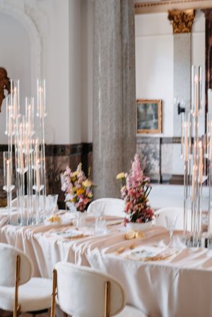Elegant wedding reception table with tall candles and floral centerpieces.
