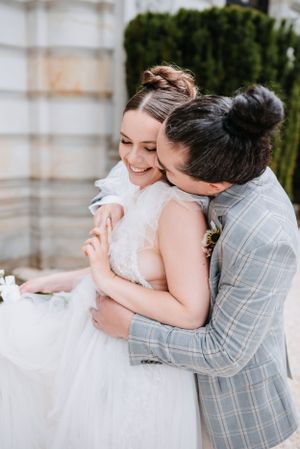Tender embrace between couple in wedding attire sharing a joyful moment.
