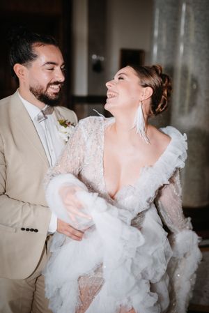 Joyful couple shares a candid moment during their wedding, with the bride wearing a stunning lace gown.