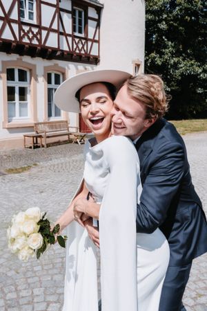 Playful moment between newlyweds outside traditional German-style building.