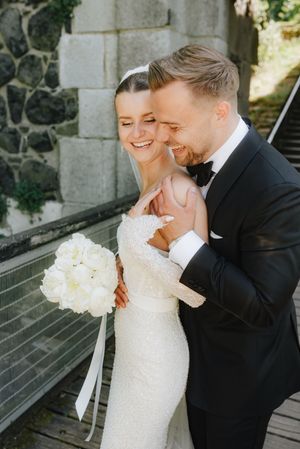 Candid wedding photography series showing joyful moments between newlyweds near a stone building.