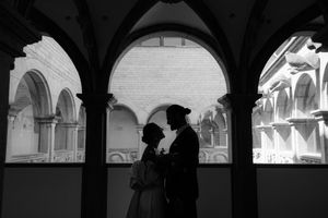 A black and white panoramic series of arched walkways and columns casting dramatic shadows.